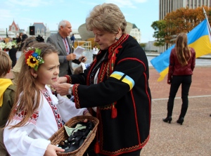 Stefa Karpishka (right) ties a ribbon of sorrow to a young community member. Credit: Olena Sadovnik 